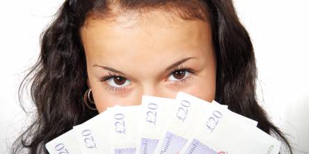 Woman looking at the camera with a fan of £20 notes.